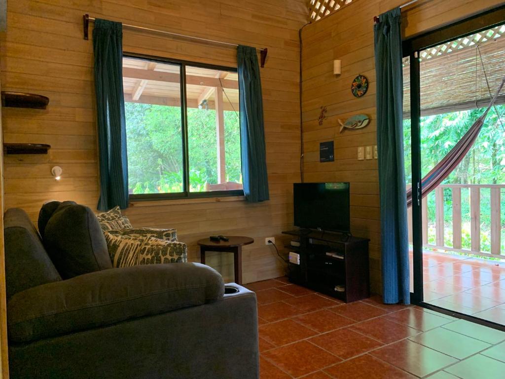 Sala de Ocean Melody 2 con sofá, TV y salida a la terraza con hamaca