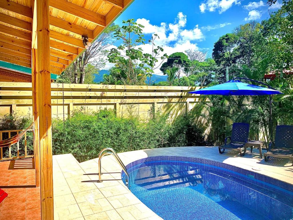 Piscina privada de Ocean Melody 3 vista desde la terraza techada, con sombrilla azul y tumbonas