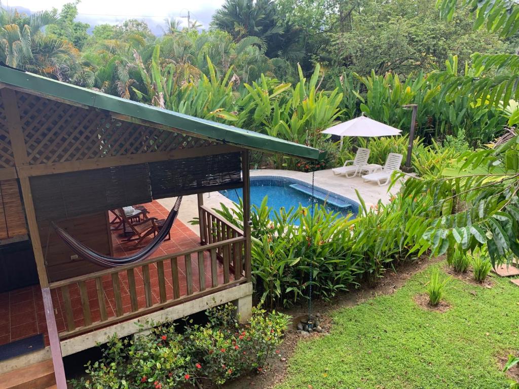 Vista de la terraza con hamaca y la piscina privada de Ocean Melody 2 rodeada de jardines