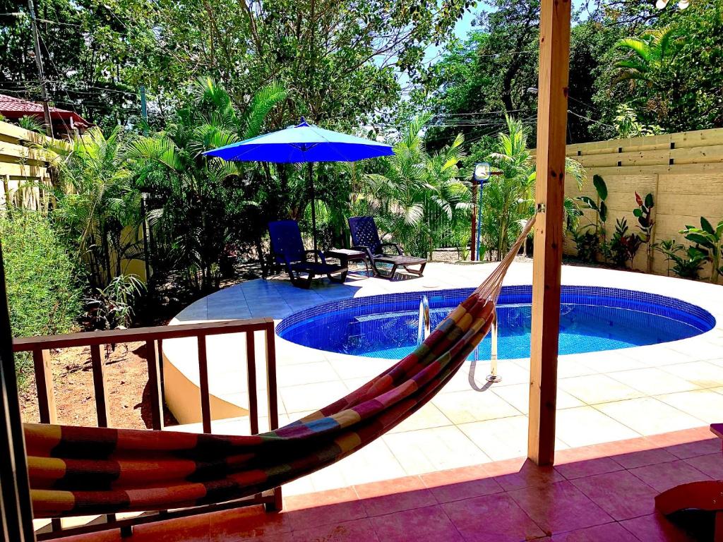 Vista de la piscina privada de Ocean Melody 3 desde la terraza, con hamaca colorida y sombrilla azul